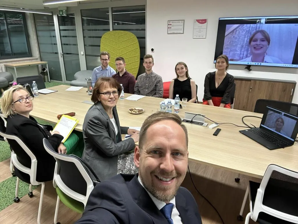 Osiem osób przy stole, dziewiąta na ekranie