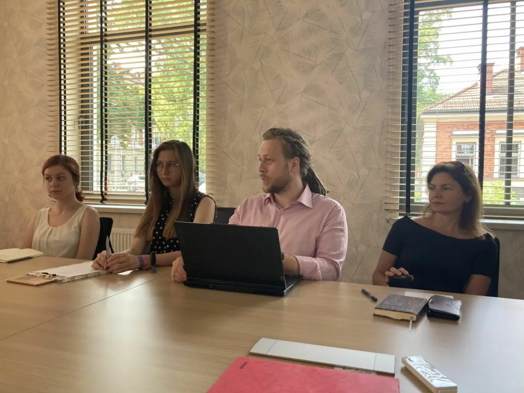 Cztery osoby, jedna z nich siedzi przed laptopem