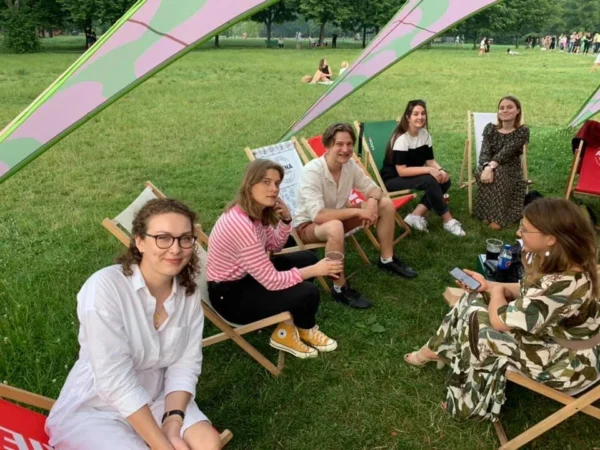 Grupa ludzi na leżakach, w tle park